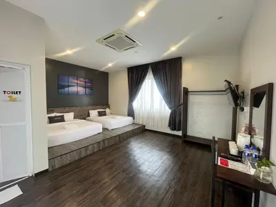a large room with two beds and a table at Capital O 91170 Kurau Bay Hotel in Kuala Kurau