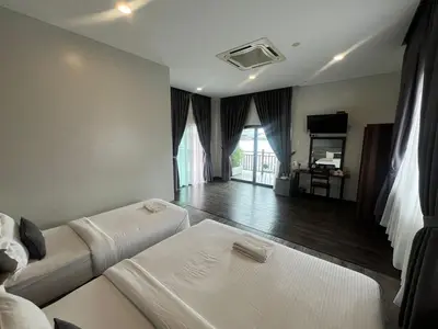 a hotel room with two beds and a television at Capital O 91170 Kurau Bay Hotel in Kuala Kurau