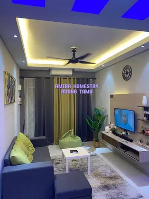 a living room with a blue couch and a tv at Amira homestay in Kampong Batu Lima