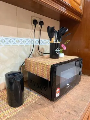 a microwave with utensils on top of it at Cozy Family Home Seberang Jaya in Kampong Bagan Dalam