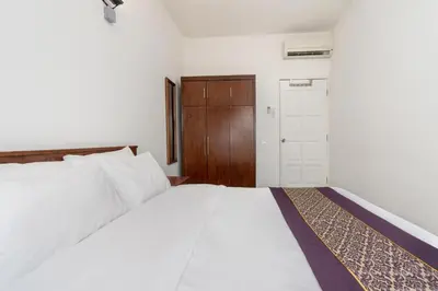 a bedroom with a white bed and a wooden door at Seaview 3 room Apartment Batu Ferringhi in Batu Ferringhi