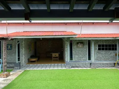 a building with a red roof and a green lawn at Galeri Merah Teratak Anak Amas in Sungai Besar