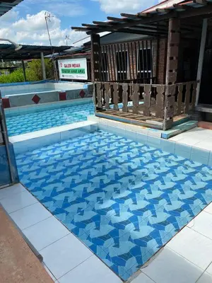 a swimming pool with blue tiles on the floor at Galeri Merah Teratak Anak Amas in Sungai Besar
