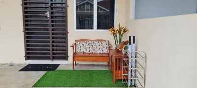 a porch with a chair and a table with a green rug at Ruma Inn Homestay Perlis in Gua Sai