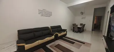 a living room with a black couch and a table at ZARI Homestay Kamunting in Gua Sai