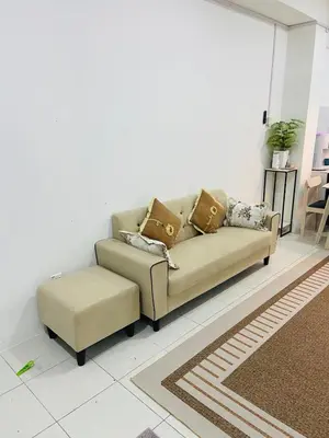 a couch and a stool in a living room at Baitul Mikhael Homestay in Kampong Ayer Melintas Besar