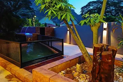 a backyard with a fireplace and palm trees at Ipoh Tambun pool villa 5br 18pax bbq mahjong in Tambun