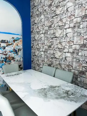 a table and chairs in a room with a stone wall at Santorini Canning Garden in Ipoh