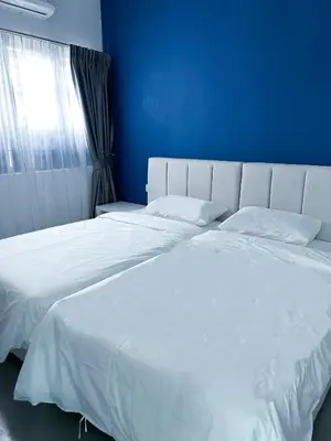 a bedroom with two white beds and a blue wall at Santorini Canning Garden in Ipoh