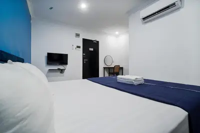 a bedroom with a white bed and a tv at BOSS Hotel in Ipoh