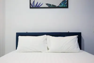 a bed with a blue headboard and white pillows at BOSS Hotel in Ipoh