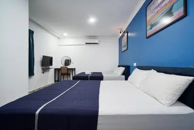 a bedroom with two beds and a blue wall at BOSS Hotel in Ipoh