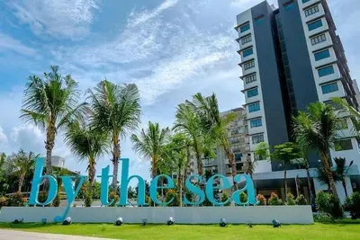 a large sign in front of a building with palm trees at By The Sea - Beachfront Bliss at Batu Ferringhi in Batu Ferringhi