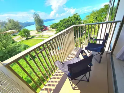 two chairs on a balcony with a view of the ocean at By The Sea - Beachfront Bliss at Batu Ferringhi in Batu Ferringhi