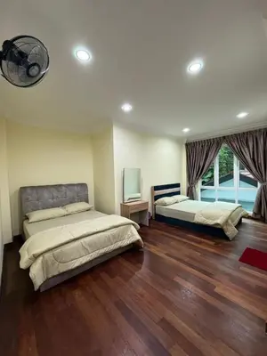 two beds in a large room with wood floors at Mossy Green Golfcourse Homestay in Tanah Rata