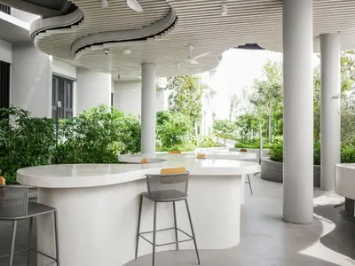 a lobby with a white counter with chairs and plants at 22 Macalisterz by MyKey in George Town