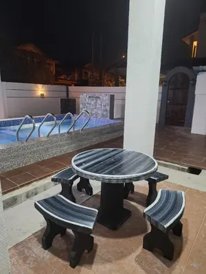 a table and two benches in front of a pool at Zehra Villa Seri Iskandar with Private Pool in Seri Iskandar