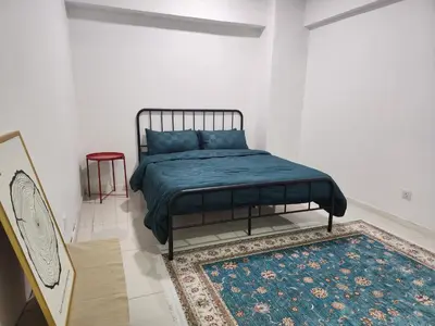 a bedroom with a bed with a blue blanket and a rug at Family Haven at Paragon in Gua Sai