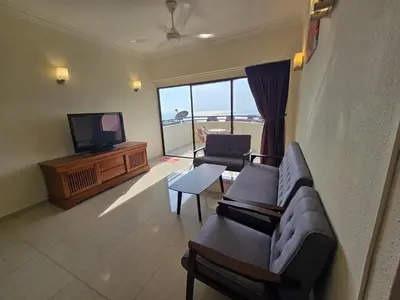 a living room with a couch and a television at Sunshine Seaview Apartment in Batu Ferringhi