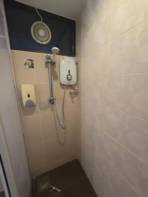 a bathroom with a shower with a toilet and a mirror at Sunshine Seaview Apartment in Batu Ferringhi