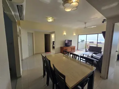 a dining room and living room with a table and chairs at Sunshine Seaview Apartment in Batu Ferringhi