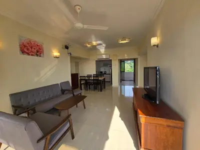 a living room with a couch and a flat screen tv at Sunshine Seaview Apartment in Batu Ferringhi