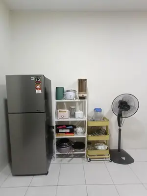 a kitchen with a refrigerator and a fan at Teratak Arissa Homestay in Sitiawan