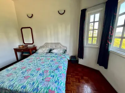 a bedroom with a bed and two windows at A Highland Retreat in Tanah Rata in Tanah Rata