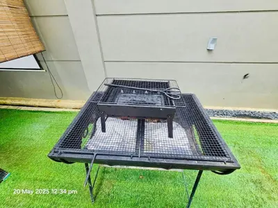 a barbecue grill sitting on top of a lawn at Cozy Villa - Private Pool, 5BR, KTV, BBQ, PS5 just 3 Mins to Batu Ferringhi Beach! in Batu Ferringhi