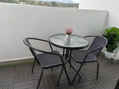 a glass table and two chairs on a balcony at FY Perumahan Makmur TR Jaya Tanah Rata in Tanah Rata