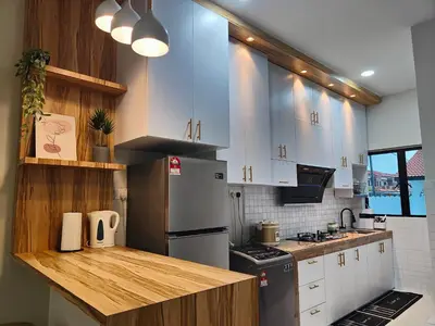 a kitchen with white cabinets and a stainless steel refrigerator at Arjuna Homestay - Batu Gajah in Batu Gajah
