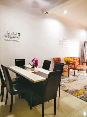 a dining room with a black table and chairs at Homestay Ustaz in Batu Gajah