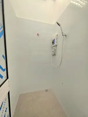 a white bathroom with a shower with a phone on the wall at Burma Home at Jalan Burma Georgetown Penang in George Town