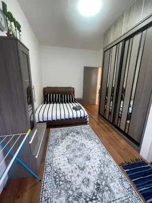 a living room with two beds and a rug at Syahoney Homestay 2 with NETFLIX in Tanah Rata