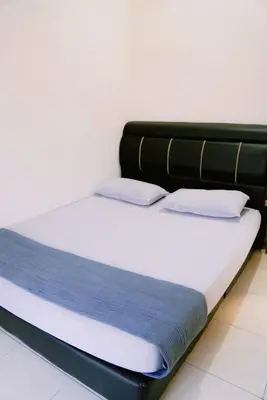 a bed with blue and white sheets and pillows at Wewe Homestay in Kampung Gajah