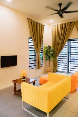 a living room with a yellow couch and a tv at Wewe Homestay in Kampung Gajah
