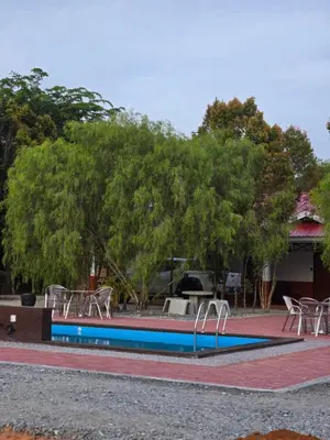a swimming pool with tables and chairs and trees at D Tasek Homestay Lenggong