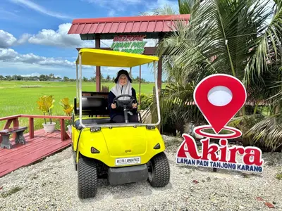 a woman driving a golf cart in front of a sign at Akira Laman Padi Tg Karang in Tanjung Karang