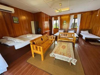 a room with two beds and chairs and wooden walls at Akira Laman Padi Tg Karang in Tanjung Karang