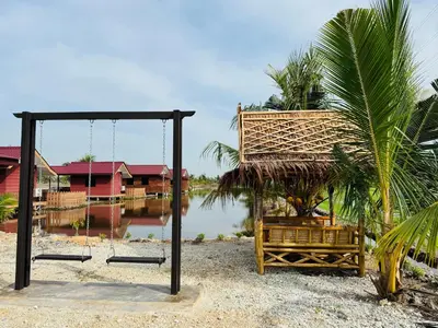 a swing on a beach next to a body of water at Akira Laman Padi Tg Karang in Tanjung Karang