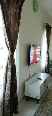 a living room with a tv and a white table at Nausha Homestay Mus-lim ONLY in Kulim