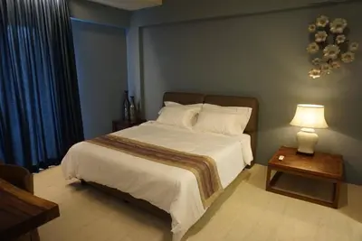 a bedroom with a bed and a table with a lamp at Ferringhi Luxury Suite @ By The Sea in Batu Ferringhi