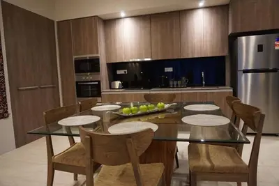a kitchen with a table and chairs and a refrigerator at Ferringhi Luxury Suite @ By The Sea in Batu Ferringhi