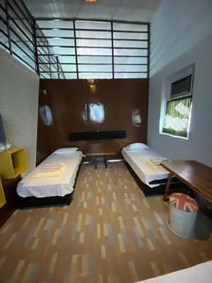 a room with two beds and a bench and a table at Bitterswiit Ladies Hostel in George Town