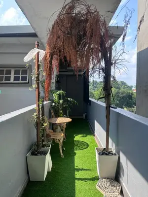 a balcony with green grass and a table and trees at Cozy Loft Bed Mini Studio Golf View in Gua Sai