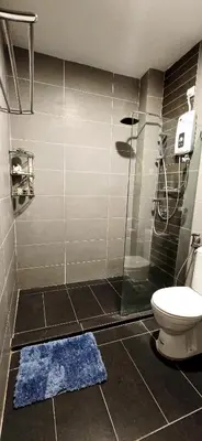 a bathroom with a shower with a toilet and a blue rug at #MyHighlandGetaway at OmniCassia Cameron Highlands in Cameron Highlands