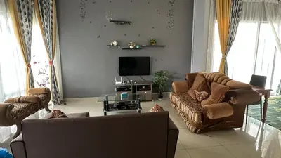 a living room with a couch and a tv at Serene Villa in Kepala Batas
