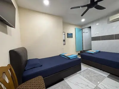 a room with two beds and a ceiling fan at Ray Yan Guesthouse Penang in Batu Ferringhi
