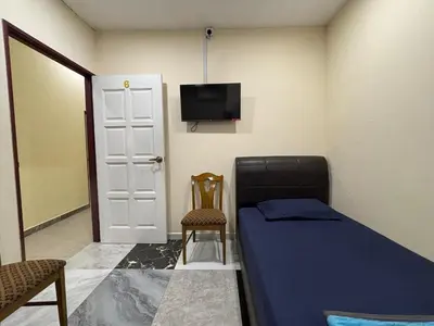 a bedroom with a bed and a tv and a chair at Ray Yan Guesthouse Penang in Batu Ferringhi