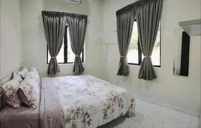 a bedroom with a bed and two windows at Homestay De'daun kulim mus'lim only in Kulim